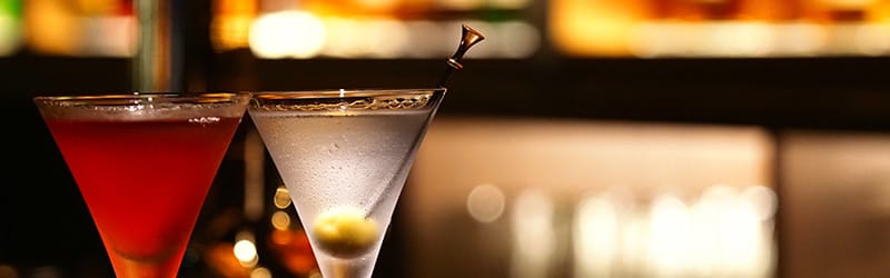 A close-up image of two cocktail glasses on a bar counter